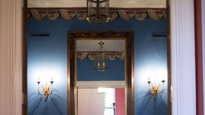 A hallway with a large mirror, a bench, and wall sconces. - Barksdale House Inn (Charleston)