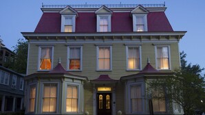 A two-story Victorian-style house with a red roof, large windows, and a front porch. - Barksdale House Inn (Charleston)