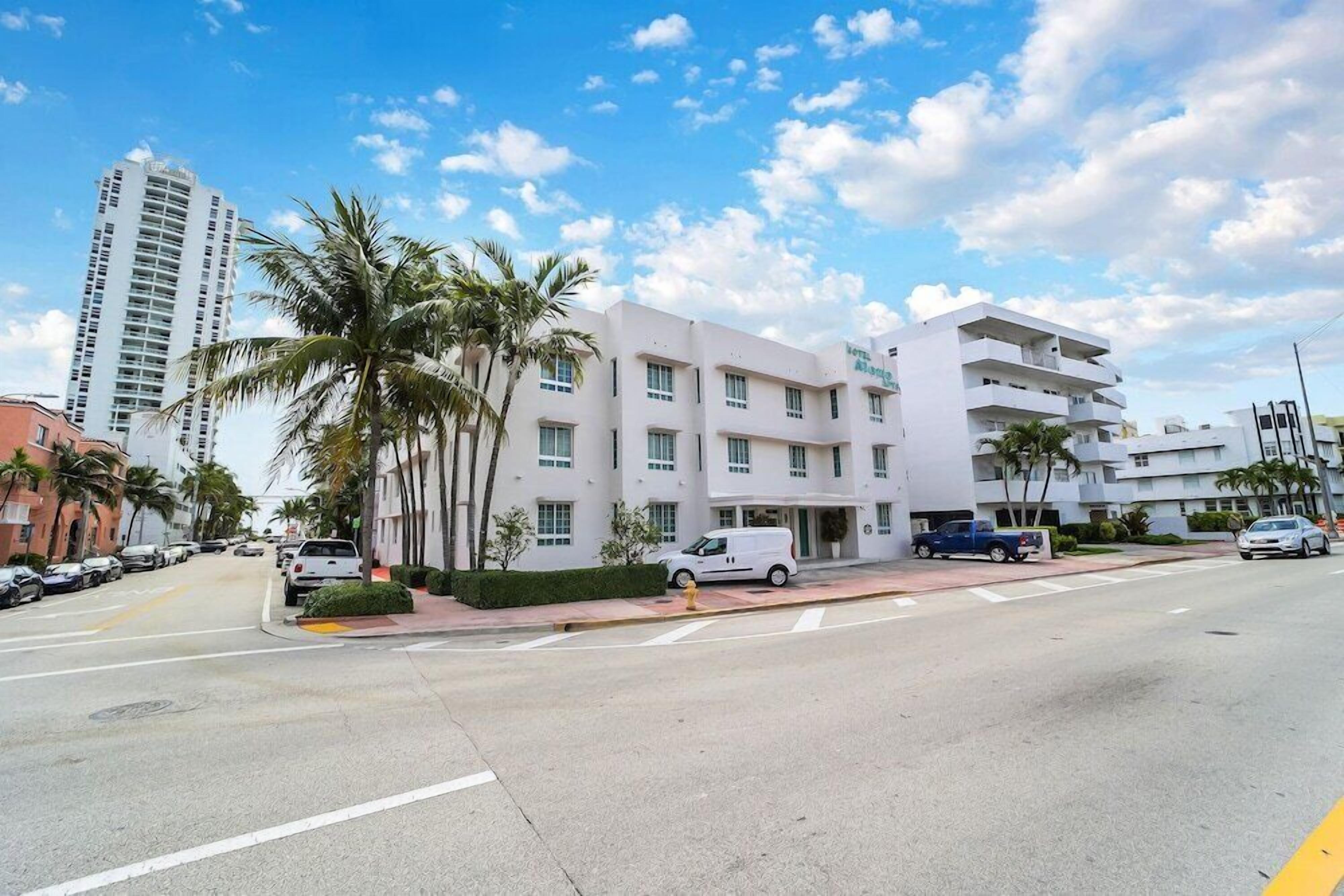 A modern hotel with multiple floors, palm trees, and a clear blue sky.