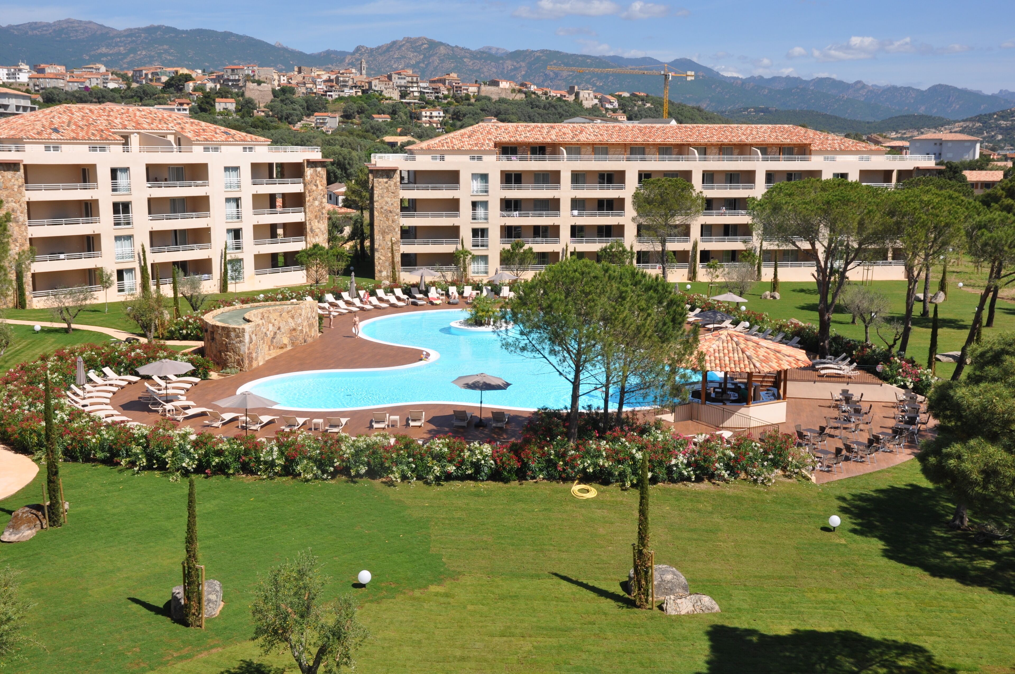 Un complexe hôtelier doté d’une grande piscine, de nombreux balcons et offrant une vue sur le paysage environnant.