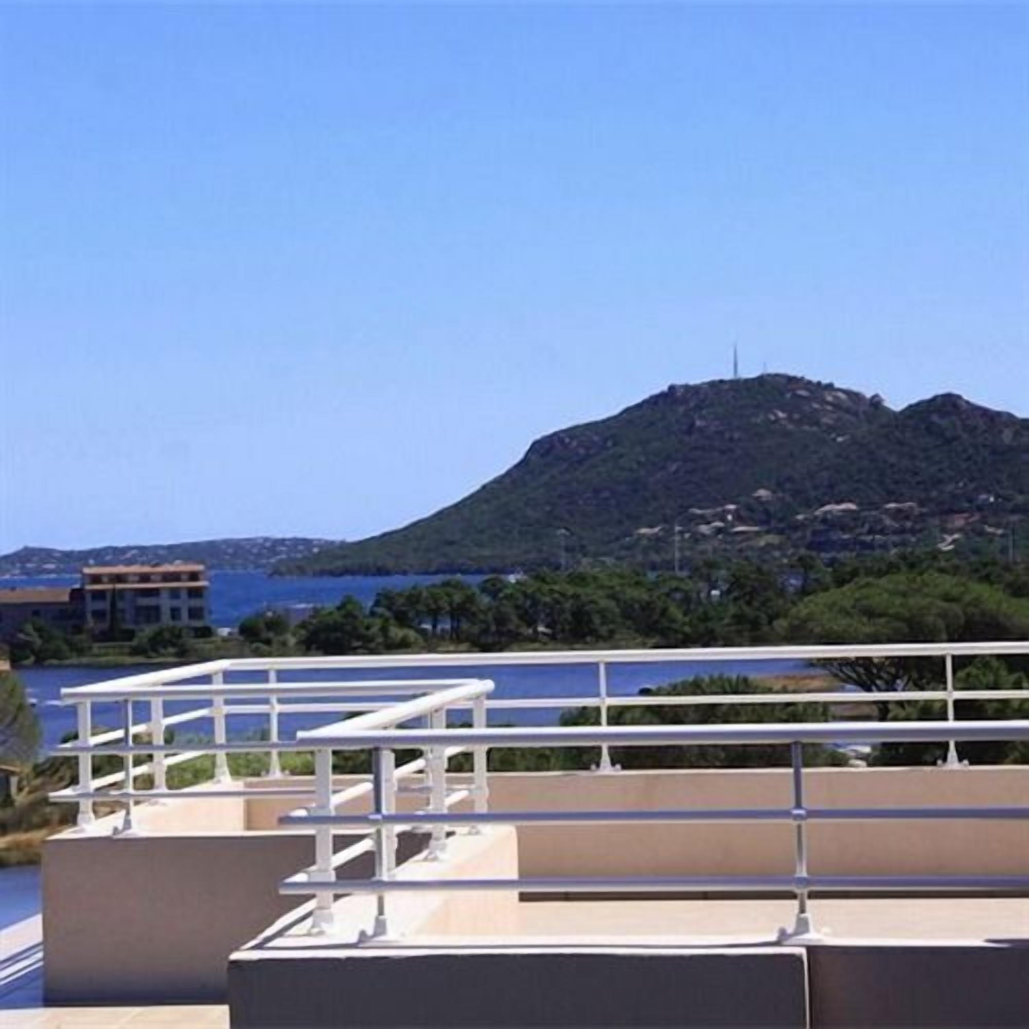 A rooftop terrace with a view of a hill and a body of water.