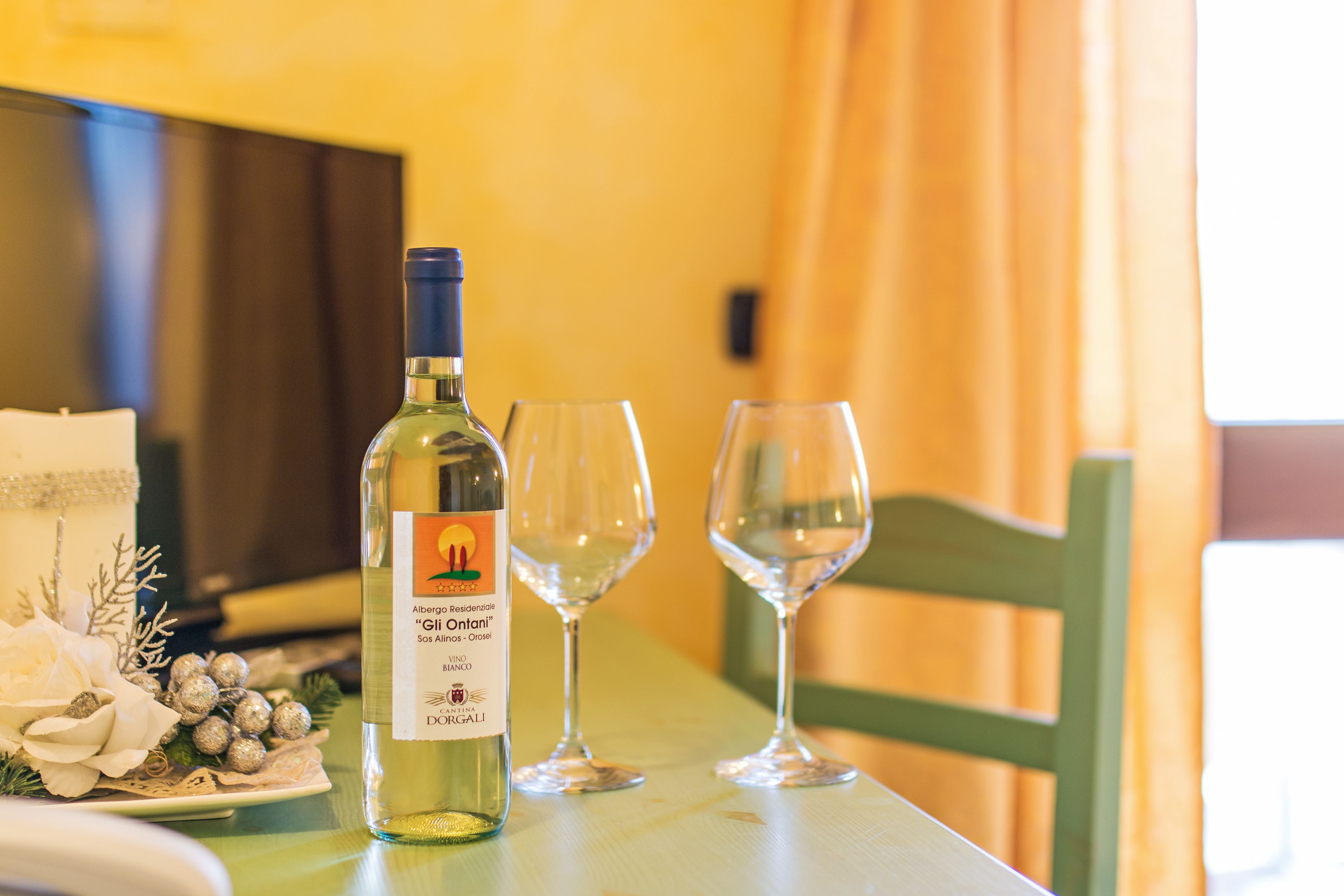Una mesa con una botella de vino, dos copas de vino vacías y un plato decorativo con flores.