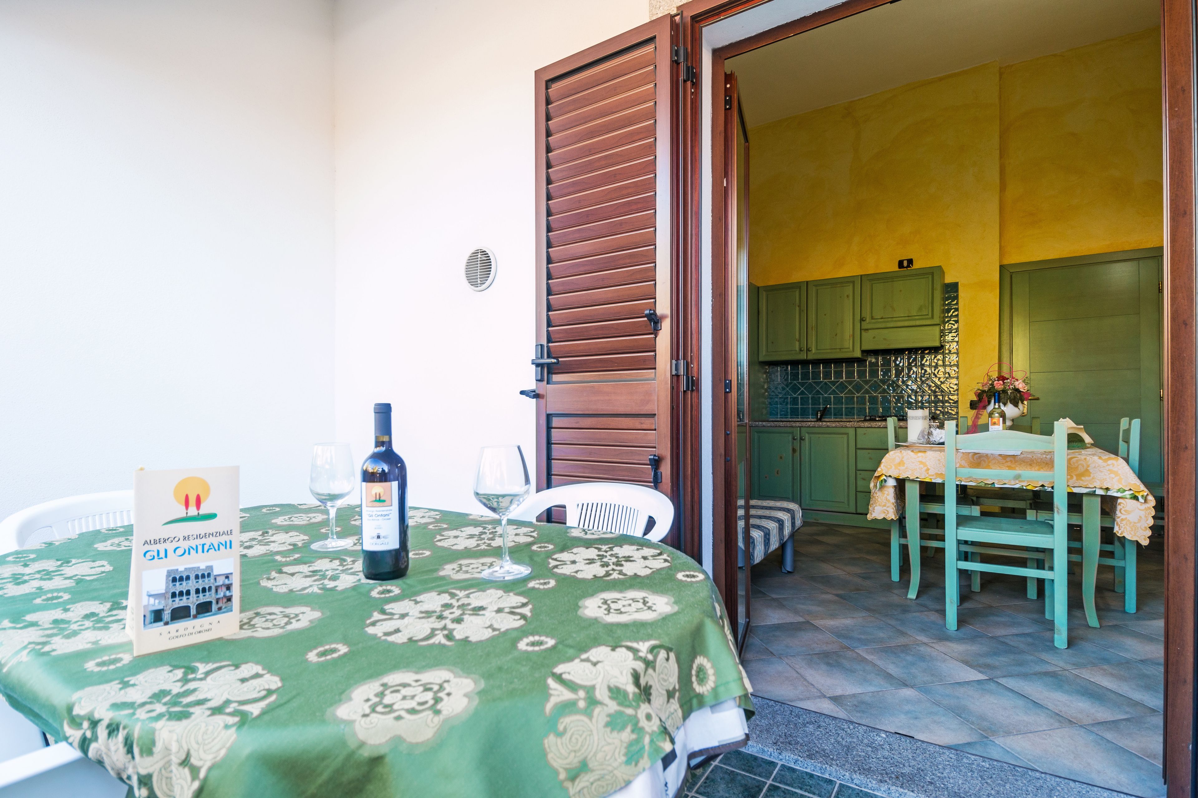 A dining area with a table set for two, a bottle of wine, and a menu stand.