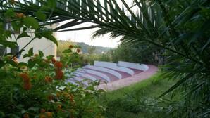 Un jardín con un sendero curvo, rodeado de follaje y plantas florecientes.