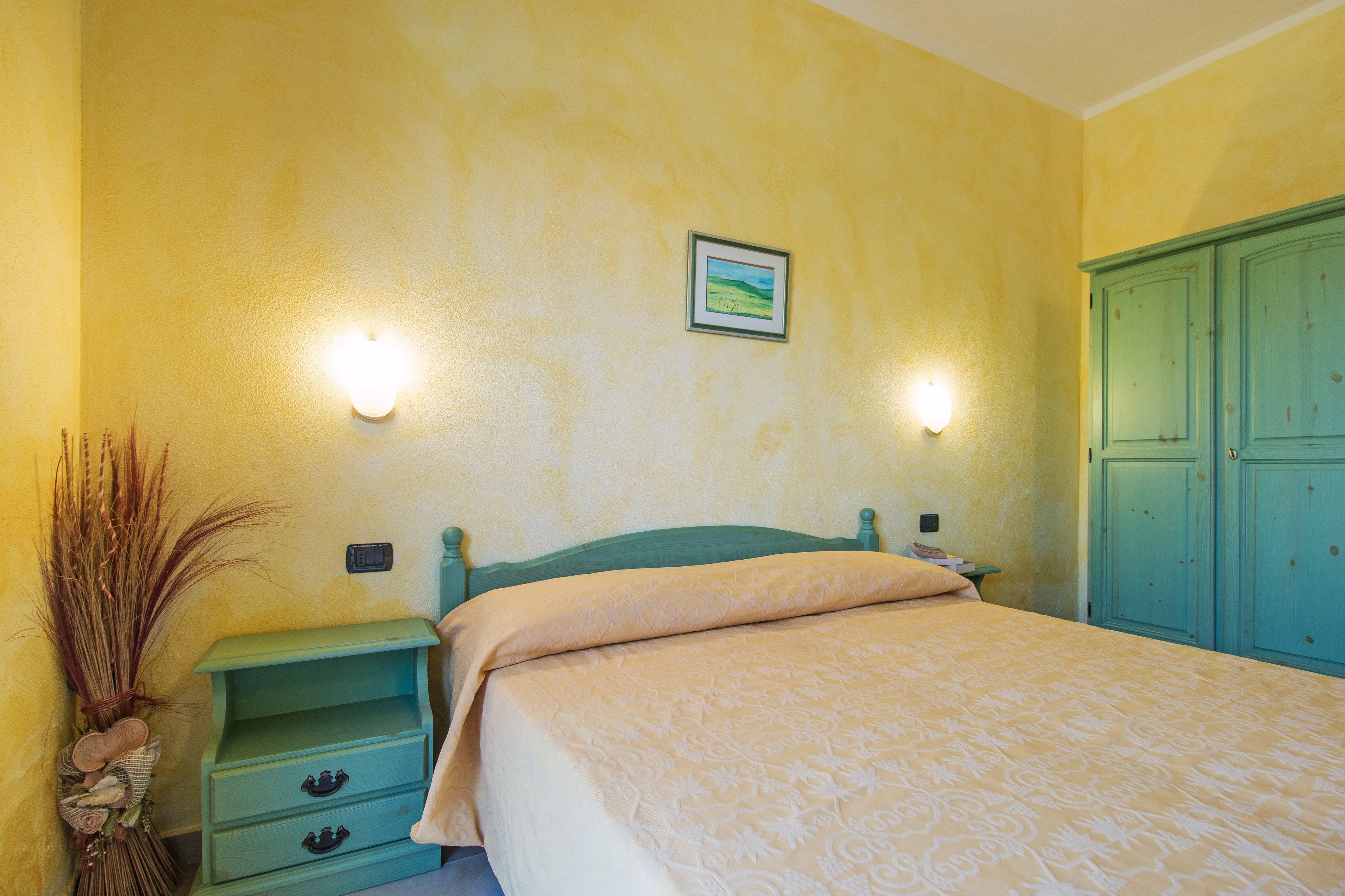 Ein Schlafzimmer mit Bett, Nachttischen, einem Schminktisch und Wandleuchten.