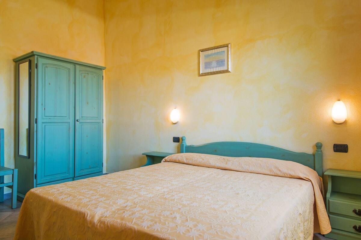 Une chambre à coucher comprenant un lit, une armoire et deux lampes fixées au mur.