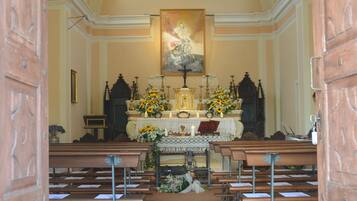 Vista del interior de una iglesia con techos abovedados, bancos y un altar central adornado con arreglos florales.