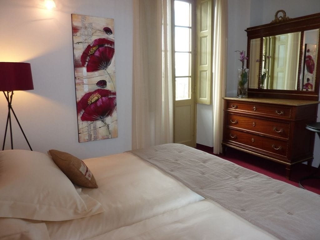 Un dormitorio con cama, cómoda, espejo y un cuadro en la pared.