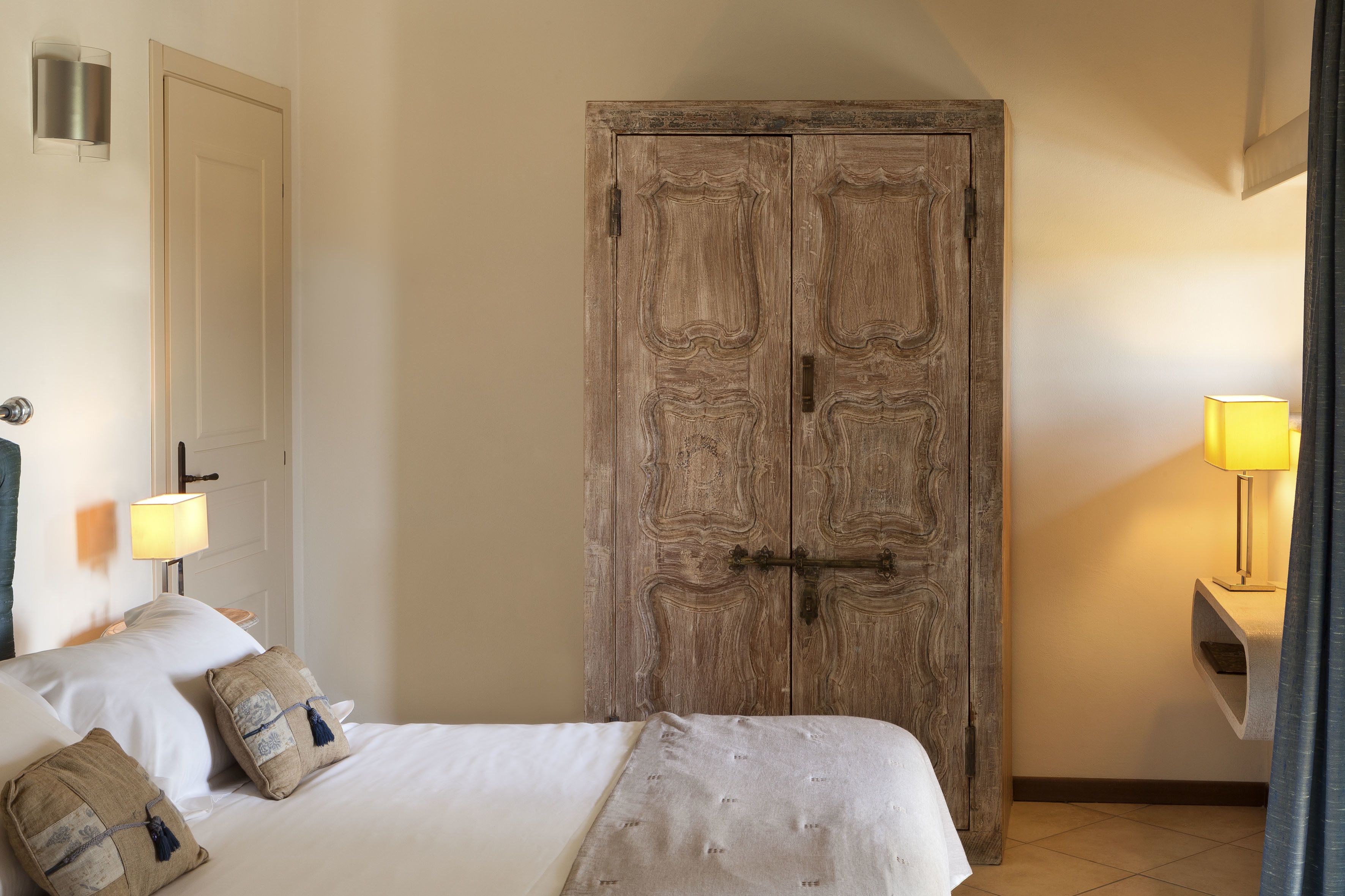 Ein Schlafzimmer mit einem Bett, Kissen, einem Kleiderschrank und einem Nachttisch mit Lampe.
