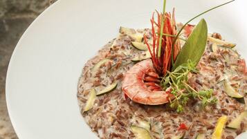 Un plato de risotto de mariscos con camarones y verduras sobre una mesa de madera.