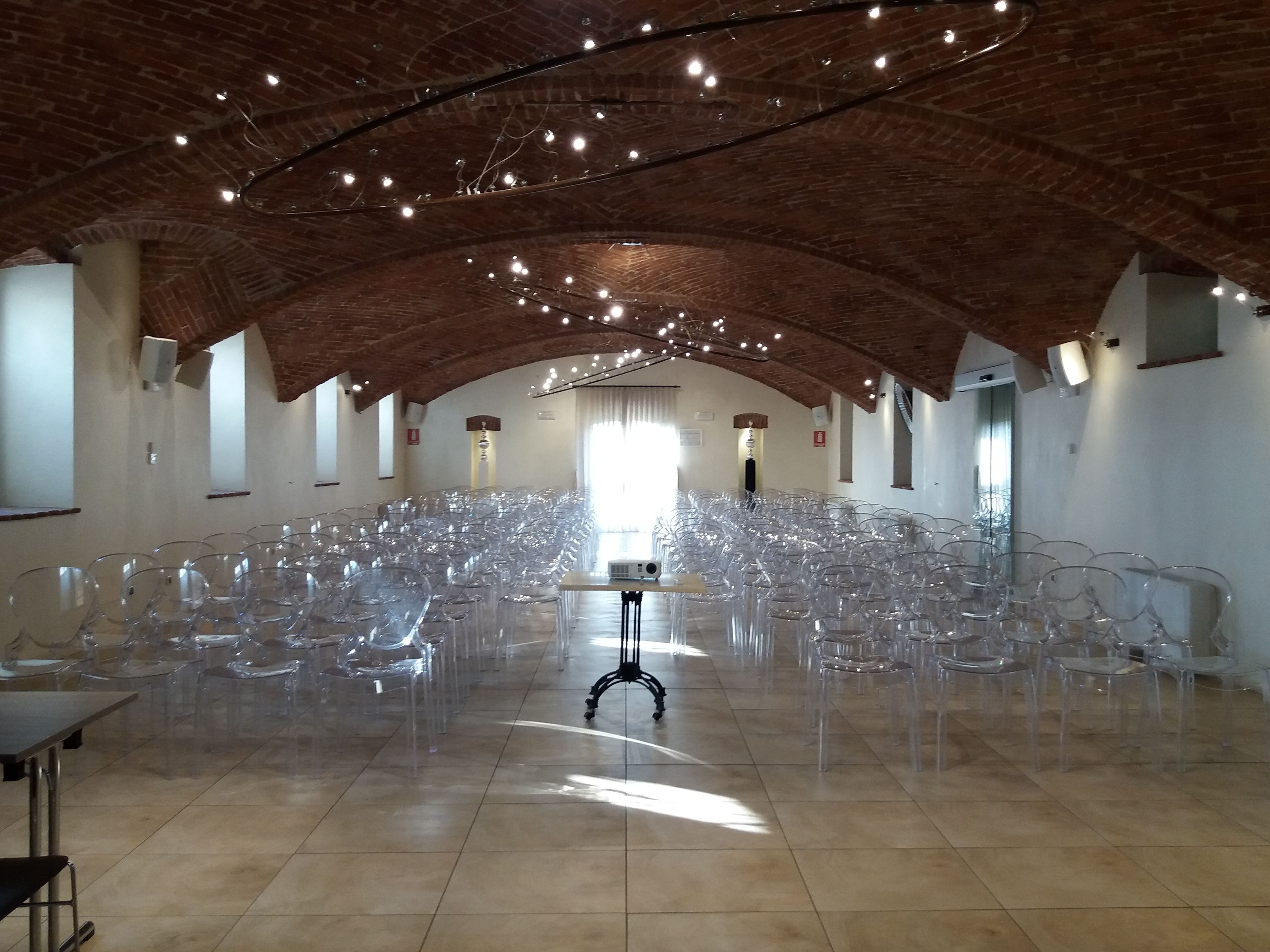 Une grande salle dotée d’un haut plafond voûté en briques et de rangées de chaises en plastique transparent.