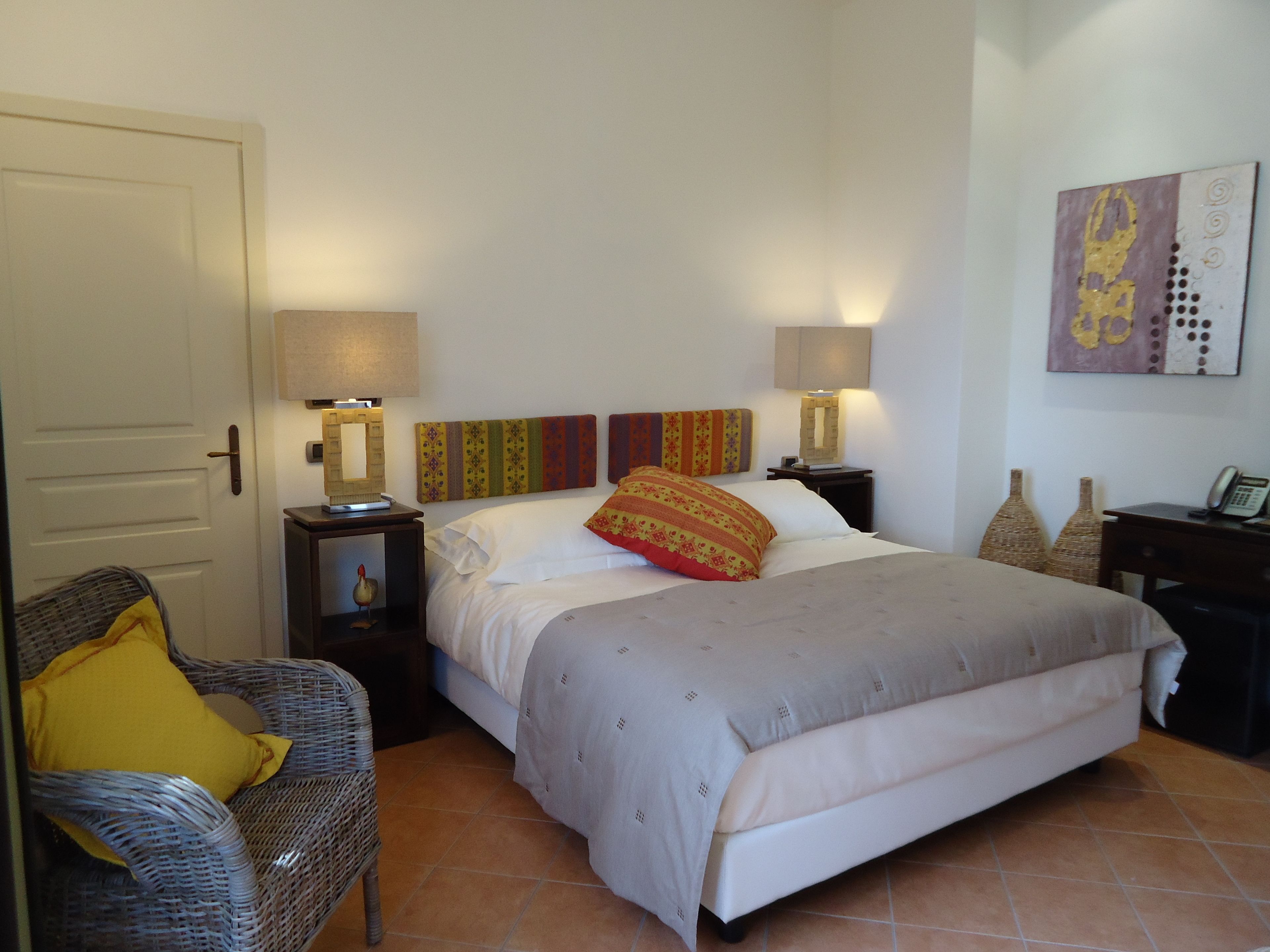 A hotel room with a bed, two bedside tables, a chair, and a door.