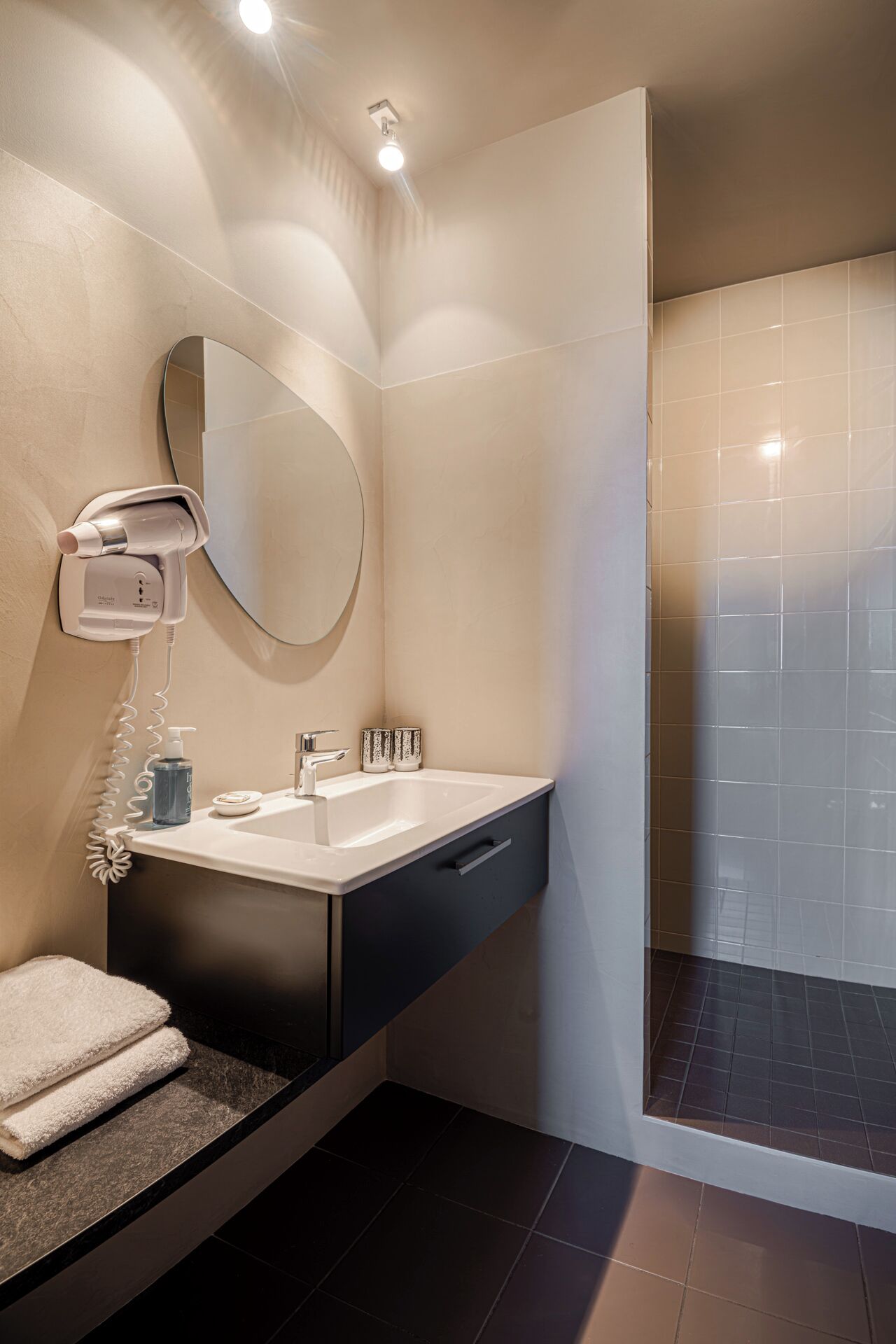 Un baño moderno con lavabo, espejo, toallero y zona de ducha.