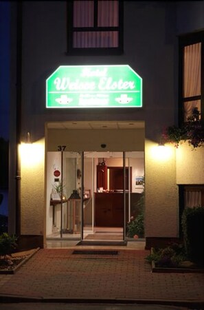 Entrada de hotel con un letrero de neón que dice "Hotel Welcome Chester".