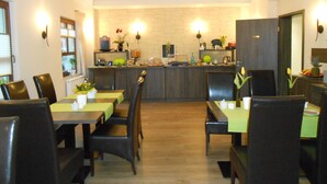 A dining area with a central bar, multiple tables, and chairs. - Hotel Weiße Elster (Zeitz)