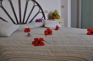 A neatly made bed with a striped bedspread and several red flowers placed on it.