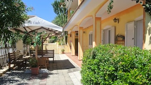 Ein Innenhof mit einer Pergola, einer Sitzgelegenheit und Topfpflanzen.