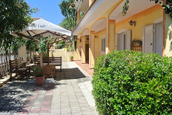 A courtyard with a pergola, seating area, and potted plants.