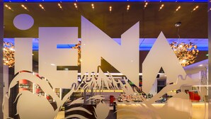 Un interior moderno con un cartel llamativo que dice 'INN', arte decorativo en la pared y una zona de bar con botellas y vasos.