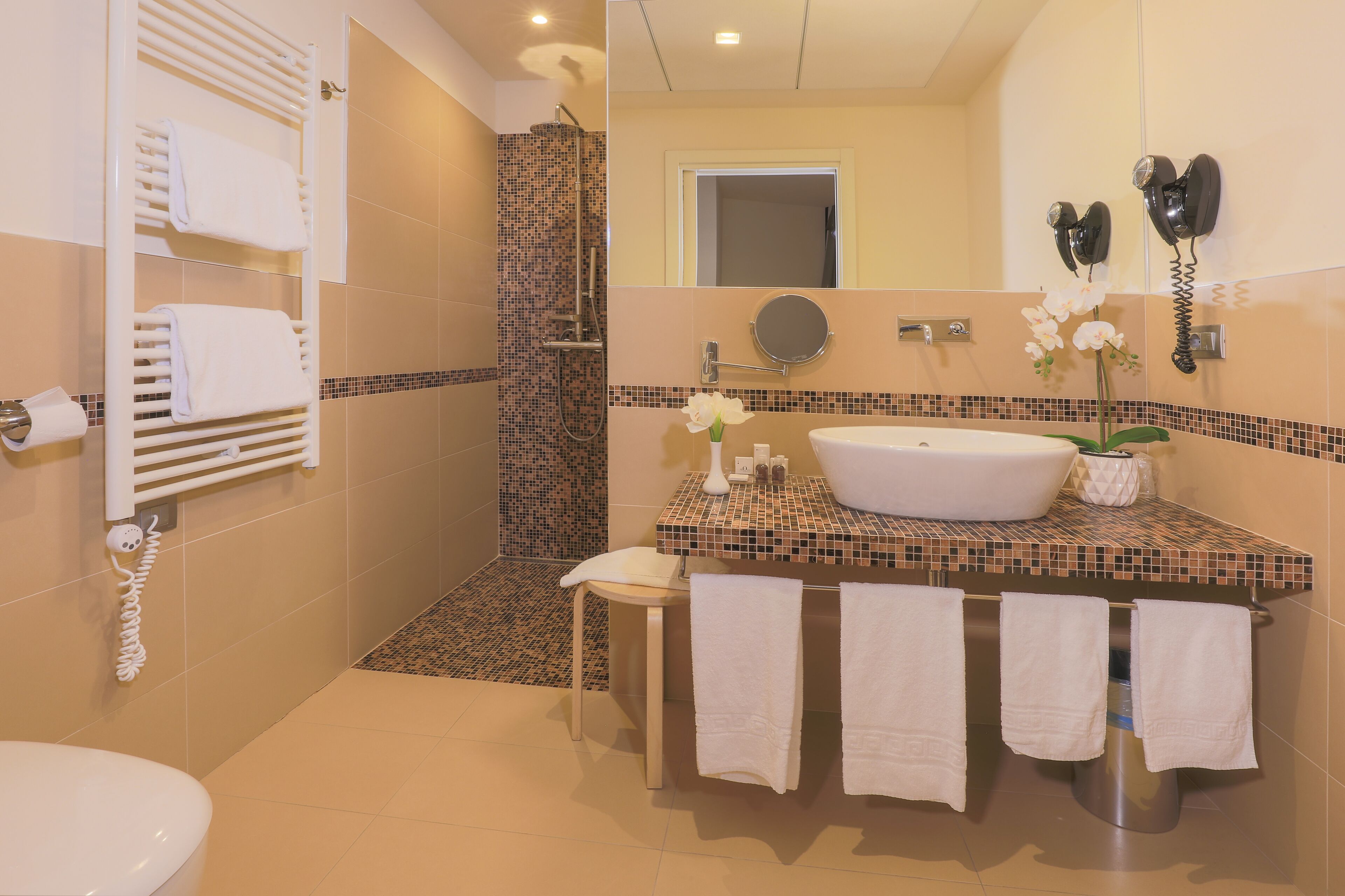 A bathroom with a shower, toilet, sink, and towel rack.