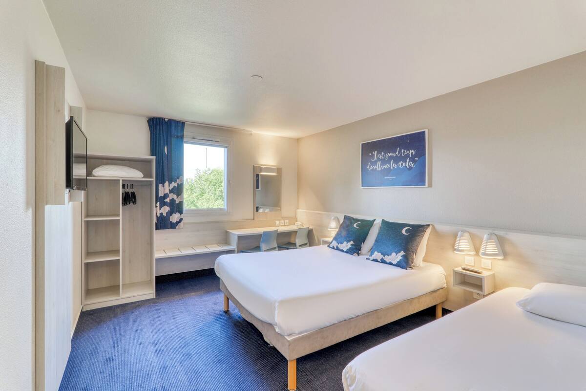 A hotel room with a bed, a desk, a wardrobe, and a bathroom.