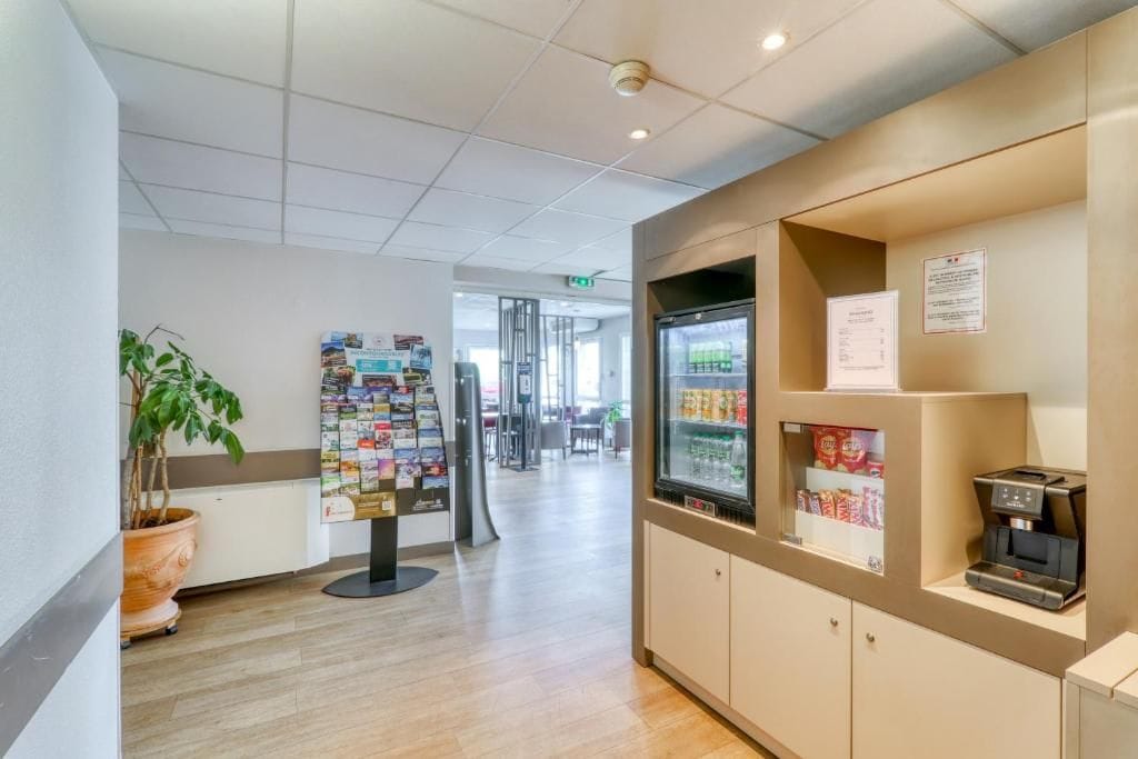 A reception area with a coffee machine, a refrigerator stocked with beverages, and a bulletin board with various notices.