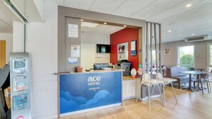 Zona de recepción de hotel con diseño moderno, que incluye un mostrador de recepción, un área de estar y vistas al exterior.