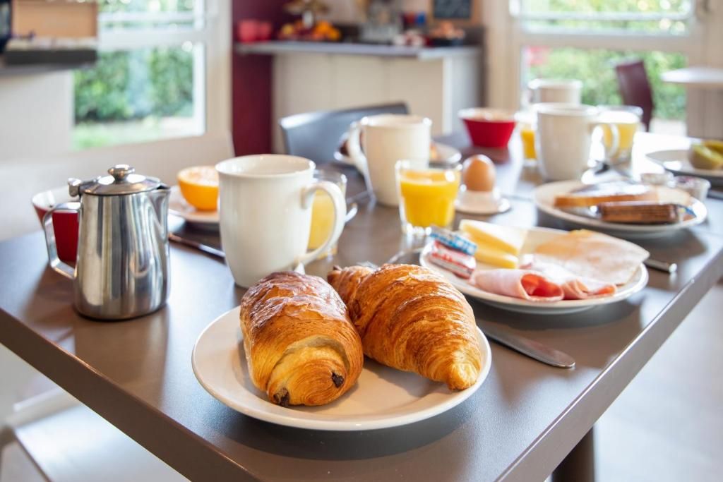 Une table de petit-déjeuner avec des croissants, du café, du jus d’orange et divers autres aliments pour le petit-déjeuner.