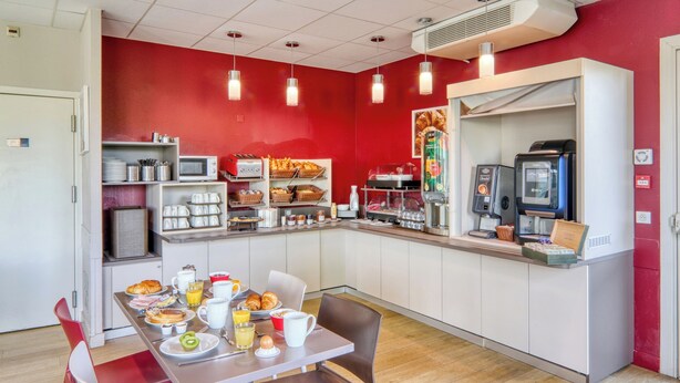 Un área de desayuno con mostrador, asientos y diversas opciones de comida y bebida.