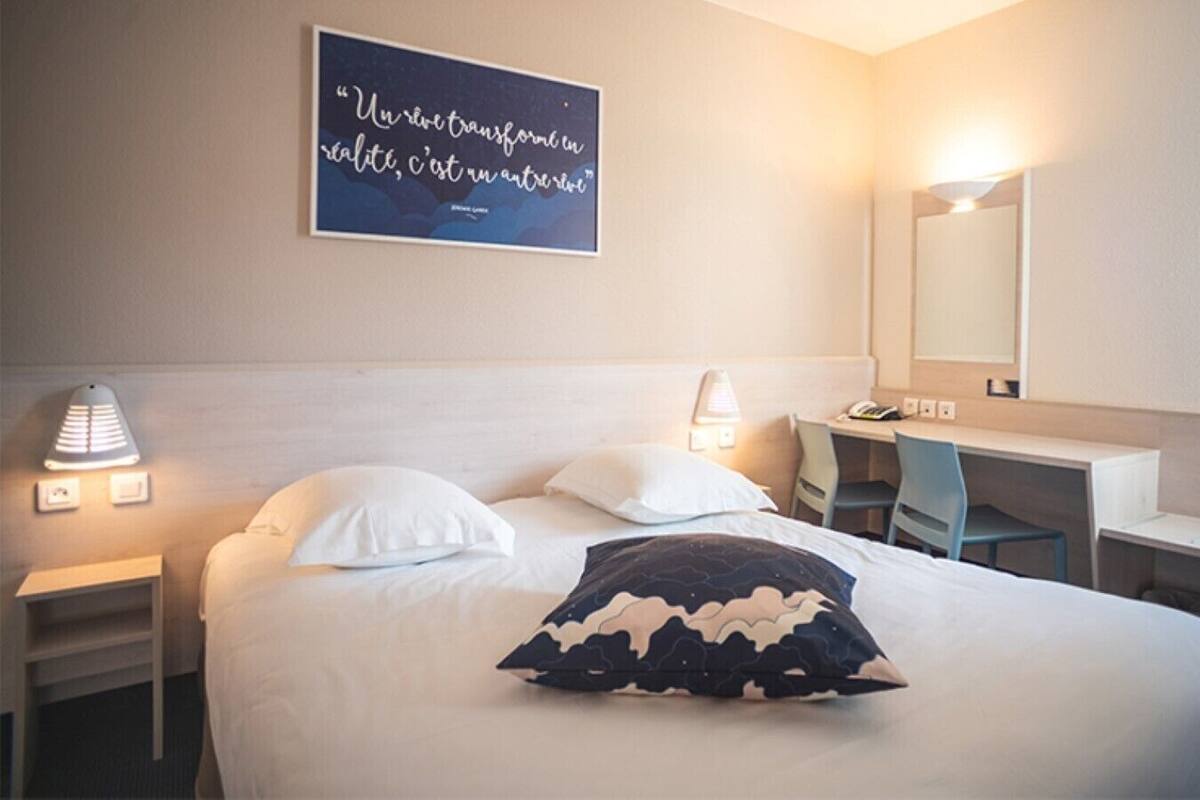 Une chambre d’hôtel comprenant un lit, deux lampes de chevet, un bureau, une chaise et un miroir.