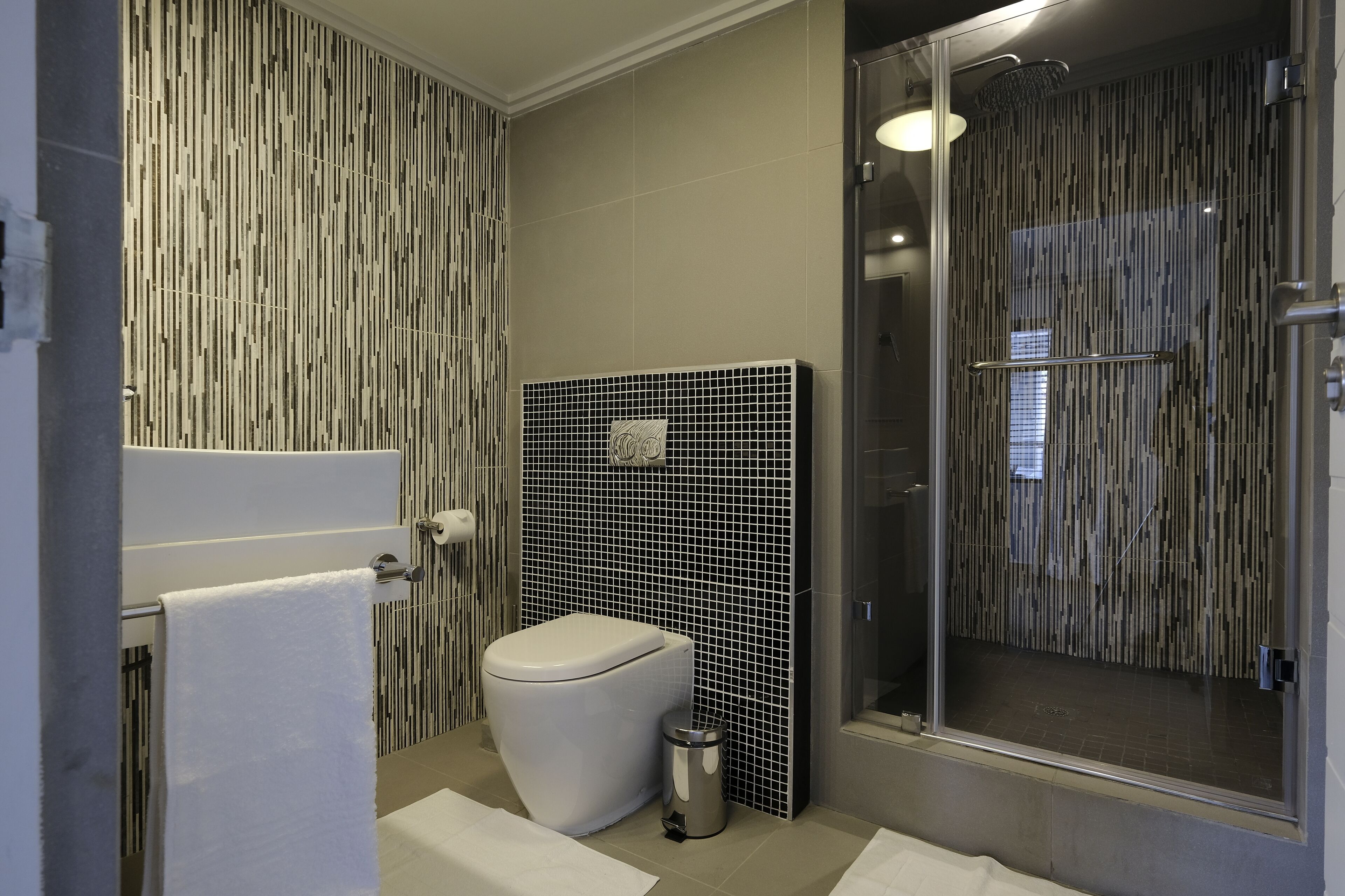 Ein modernes Badezimmer mit Toilette, Duschkabine und Fliesen.