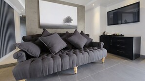 A modern living room with a dark grey sofa, a large wall-mounted TV, and a minimalist design.