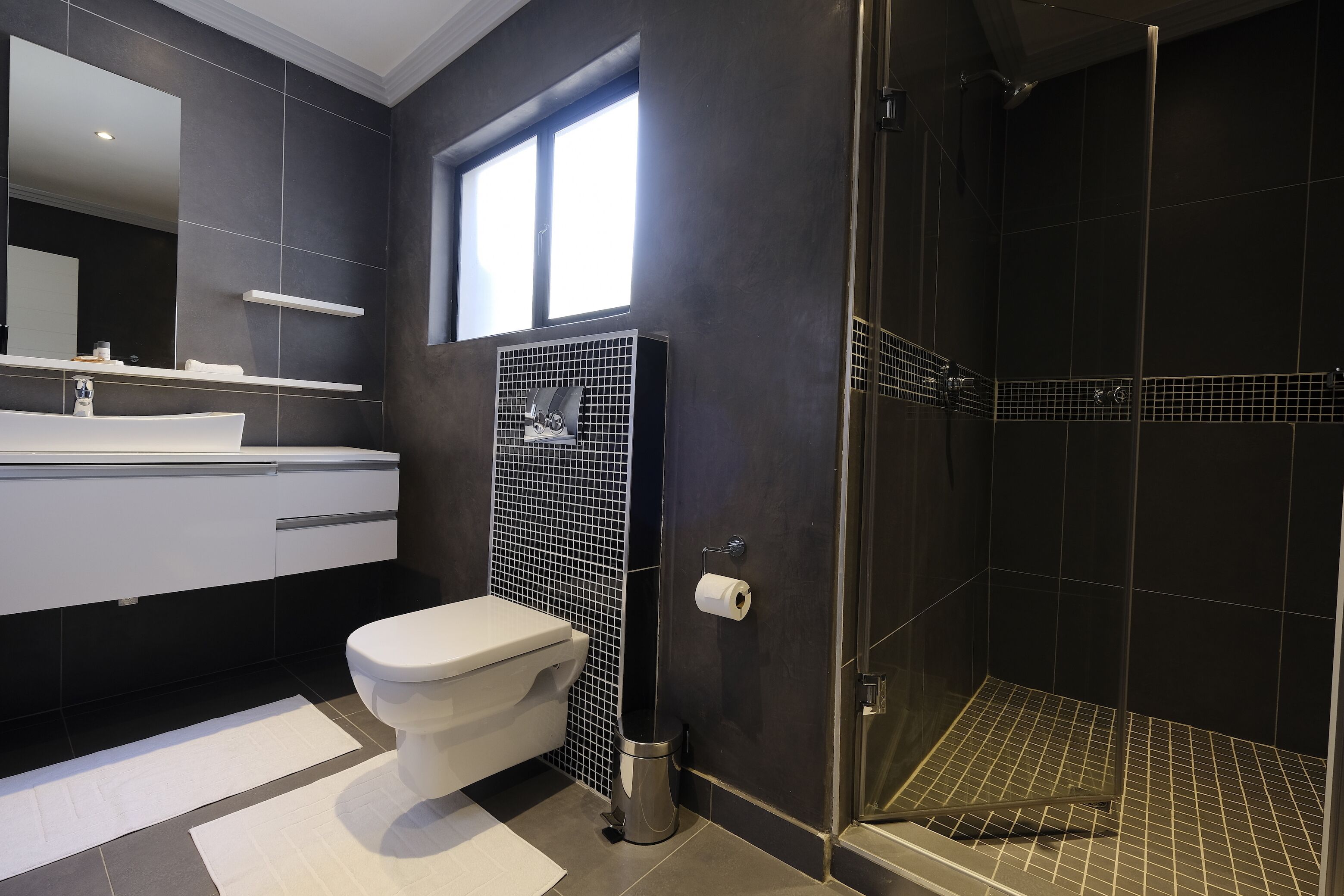 A modern bathroom with a toilet, sink, and shower.