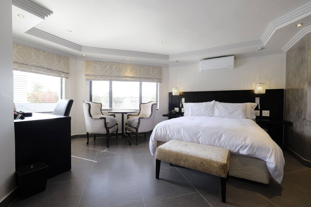 Une chambre d’hôtel avec un grand lit, un bureau, une chaise et une petite table.