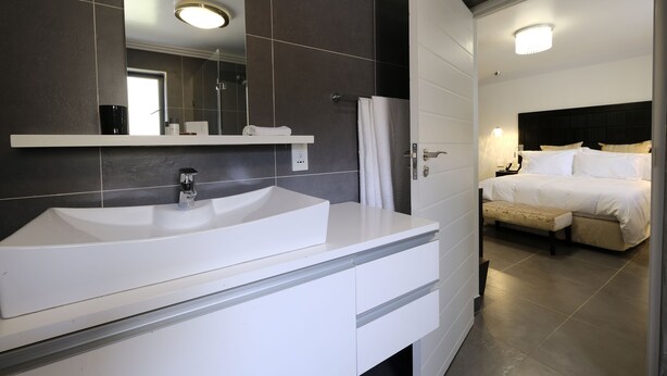 A modern bathroom with a large white sink, a mirror, and a shower area.