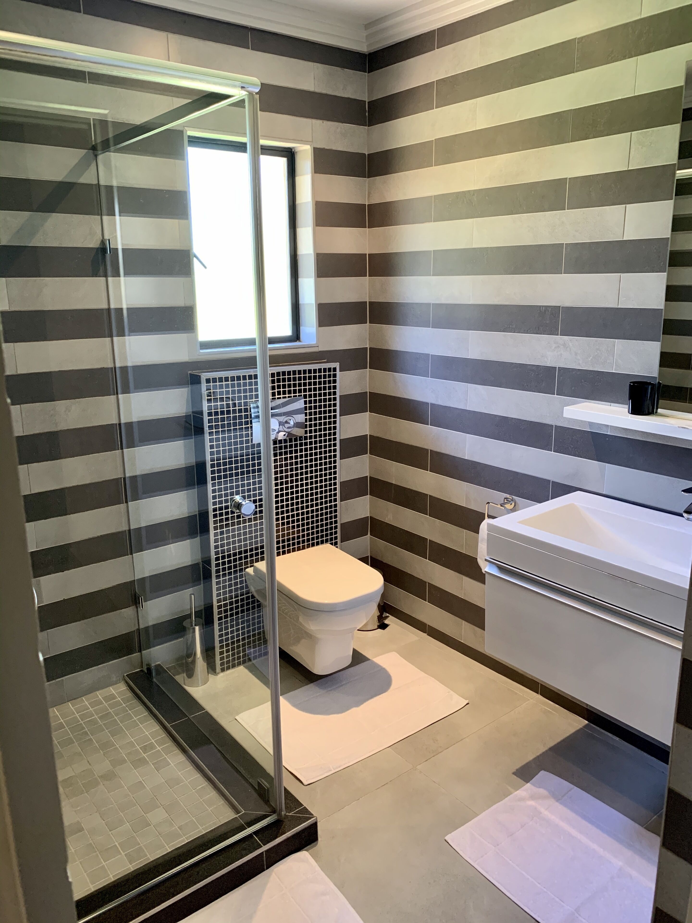 Un baño moderno con cabina de ducha de vidrio, inodoro y lavamanos.