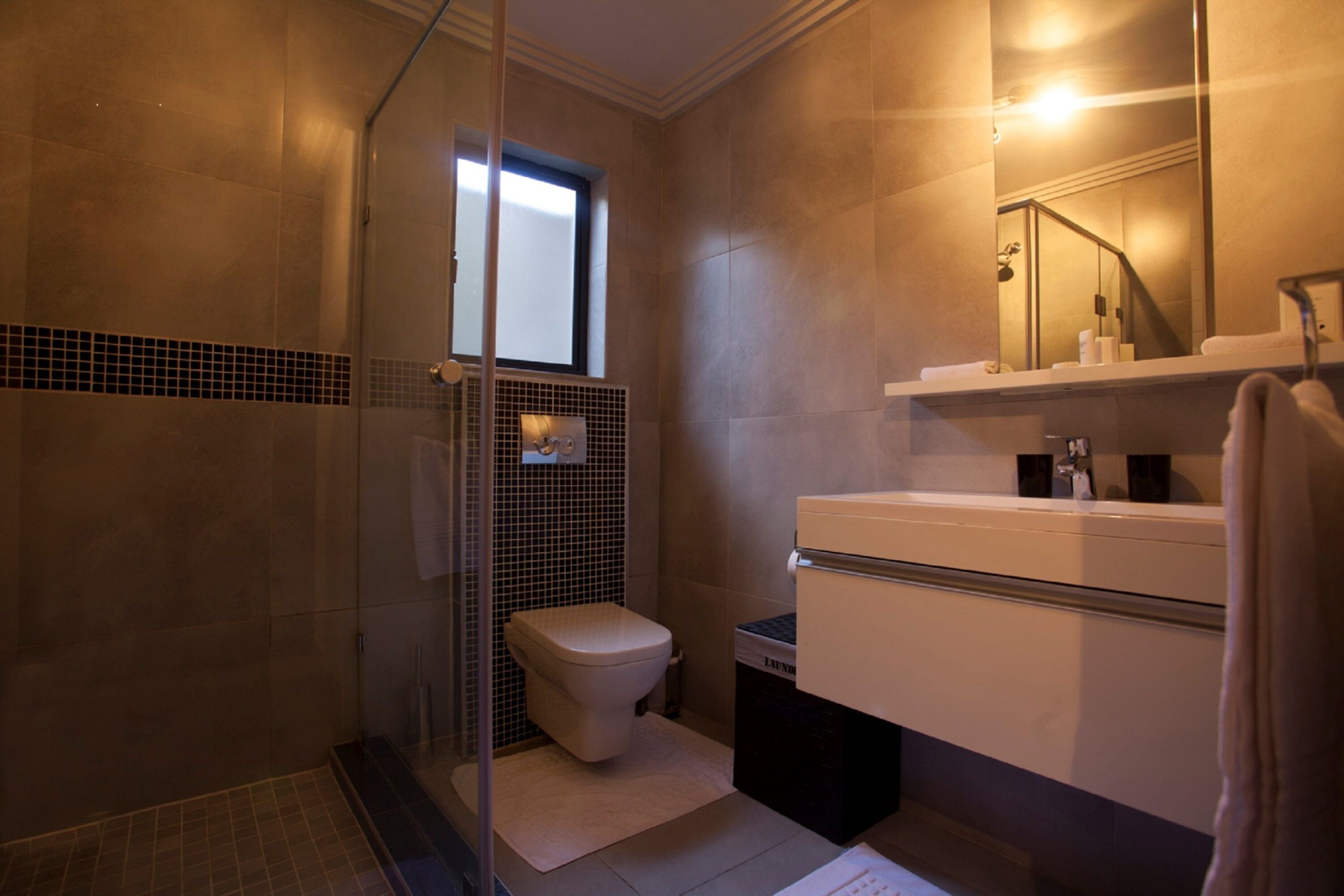 Un baño moderno con cabina de ducha de vidrio, un inodoro y un lavabo con espejo.
