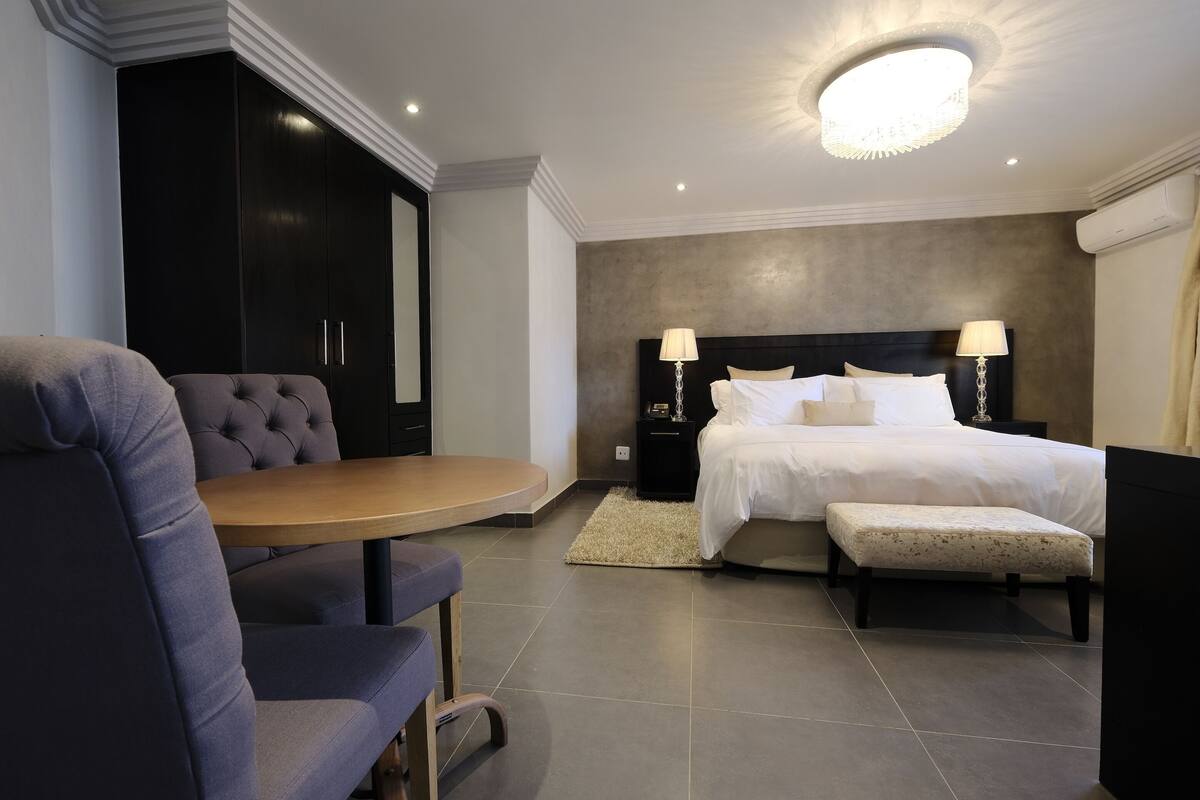 Une chambre d’hôtel moderne dotée d’un grand lit, d’un coin salon avec une table et d’une armoire.