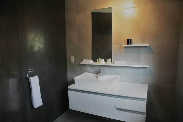 A modern bathroom with a large mirror, a white sink, and a towel rack. - Villa Moyal (Johannesburg)