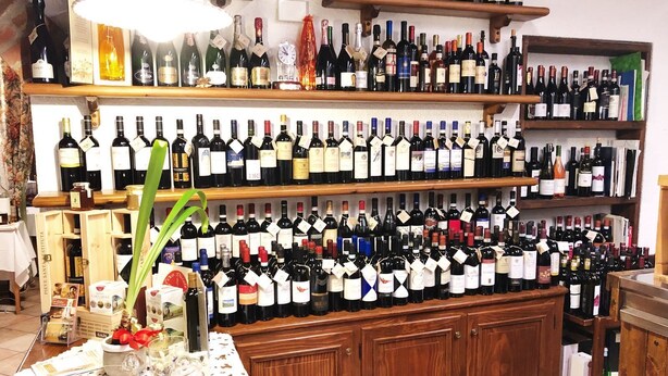 A wine shop with multiple shelves stocked with various wine bottles. - Da Carla Trattoria con Locanda (Gambolo)
