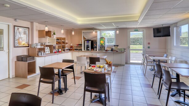 A modern cafe with a central counter, seating area, and a TV mounted on the wall.
