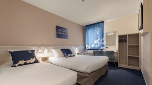 A hotel room with two beds, a desk, a chair, a wardrobe, and a wall-mounted TV. - Ace Hotel Clermont-Ferrand La Pardieu (Clermont-Ferrand)