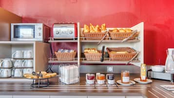 A breakfast buffet with bread, pastries, and condiments.