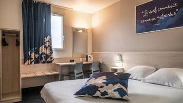 Habitació d'hotel amb un llit, escriptori, cadira, armari i una paret amb una cita.