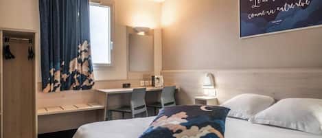 Una habitación de hotel con cama, escritorio, silla, armario y una pared con una cita.