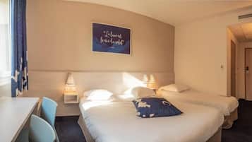 A hotel room with two beds, a desk, and a chair. There is a wall-mounted artwork and a door to the right.