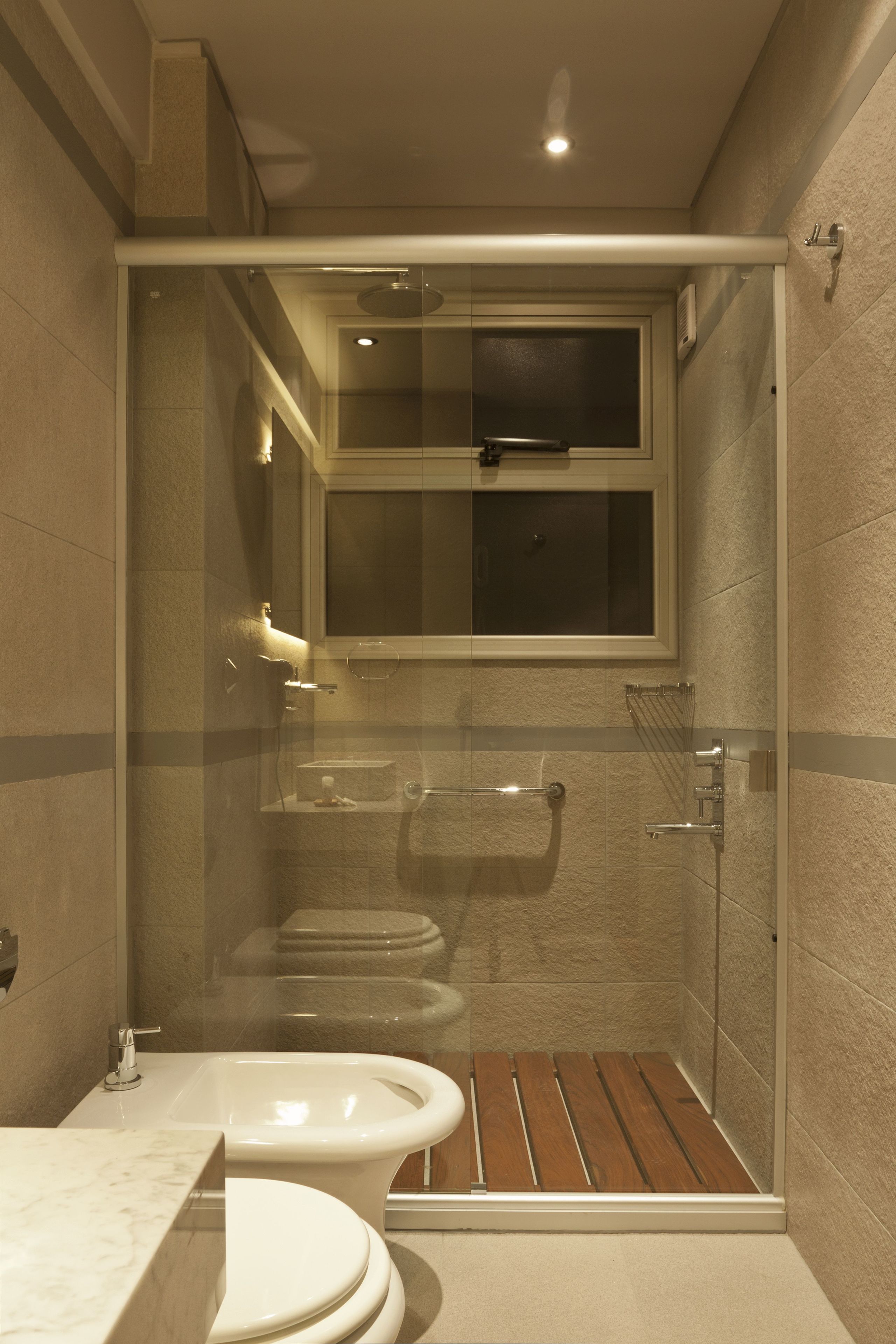 A modern bathroom with a glass-enclosed shower, a bidet, and a toilet.