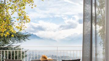 A balcony with two wicker chairs, a small round table, and a book.