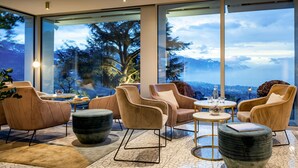 A modern interior with large windows, plush seating, and a view of mountains. - Hotel du Leman (Jongny)