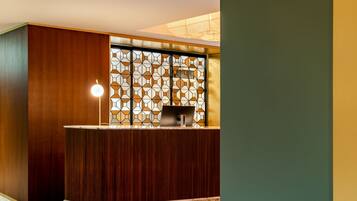 A reception area with a wooden reception desk, a patterned glass partition, and a floor with a geometric tile pattern.